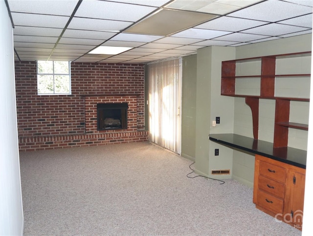 interior space featuring a fireplace, light colored carpet, and a drop ceiling