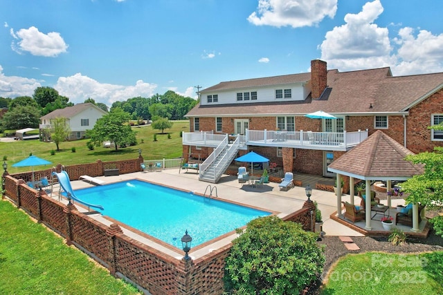 view of pool with a lawn, a water slide, a gazebo, a wooden deck, and a patio area