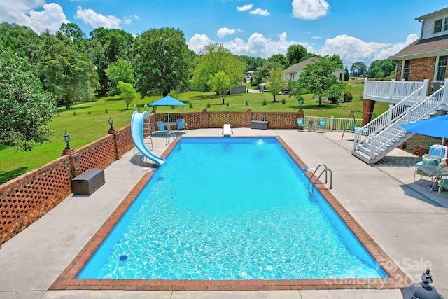 view of swimming pool featuring a yard, a patio, and a water slide