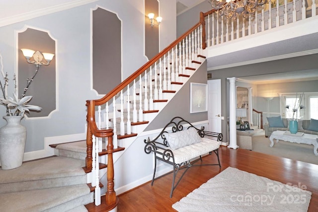 staircase featuring hardwood / wood-style flooring, ornamental molding, and decorative columns