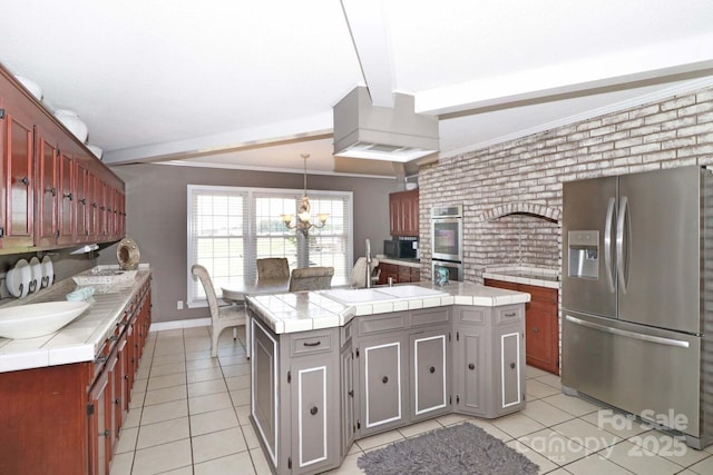 kitchen with pendant lighting, light tile patterned floors, stainless steel appliances, a center island, and tile countertops