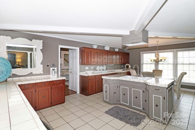 kitchen featuring sink, tile countertops, pendant lighting, beam ceiling, and a kitchen island with sink