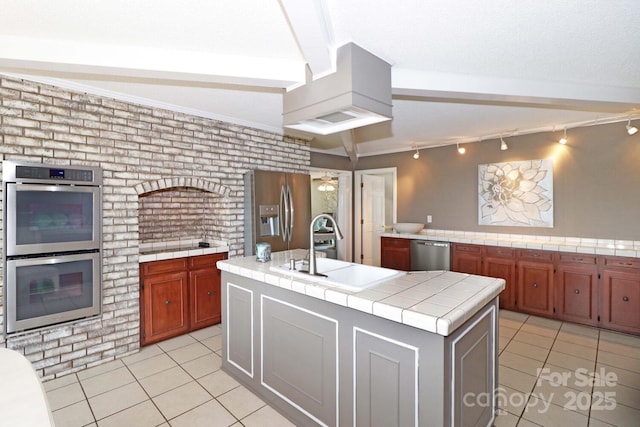 kitchen with sink, a center island with sink, light tile patterned floors, appliances with stainless steel finishes, and tile counters