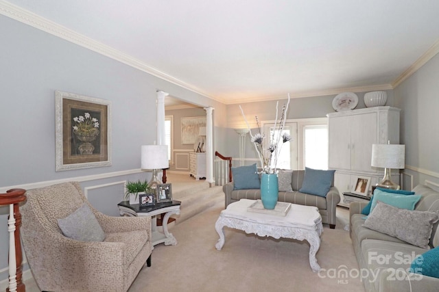 carpeted living room with crown molding and decorative columns