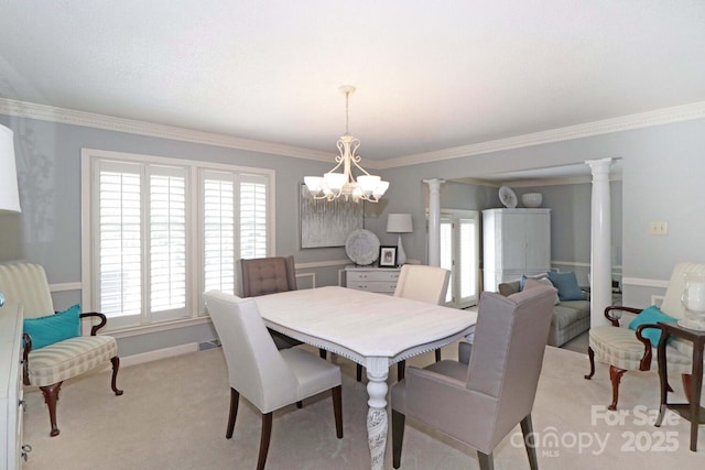 dining space with light carpet, crown molding, a chandelier, and ornate columns