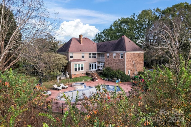 rear view of house with a patio area and a swimming pool with hot tub