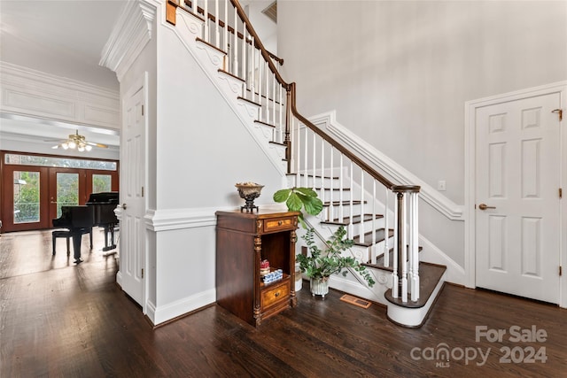 stairway featuring crown molding, french doors, hardwood / wood-style flooring, and a high ceiling