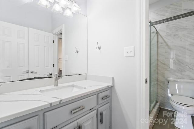 bathroom with a shower with shower door, vanity, and toilet