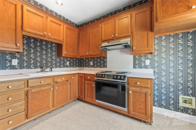 kitchen featuring sink, light tile patterned floors, and black range oven