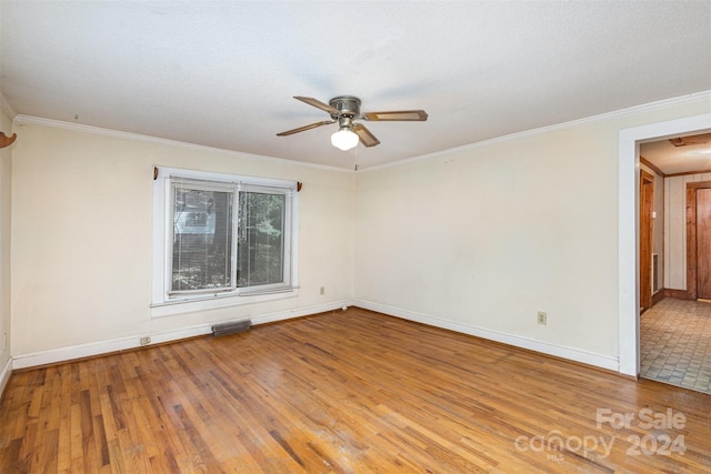 empty room featuring a textured ceiling, ceiling fan, wood-type flooring, and ornamental molding