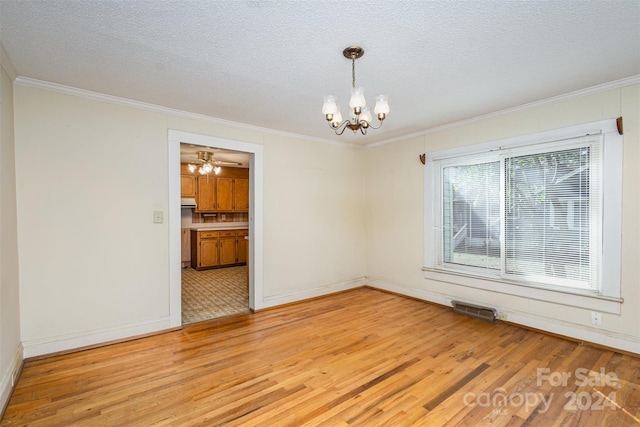 empty room featuring a textured ceiling, an inviting chandelier, light hardwood / wood-style flooring, and crown molding