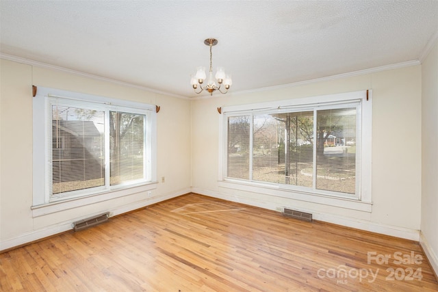 unfurnished dining area featuring a wealth of natural light, hardwood / wood-style floors, and a chandelier