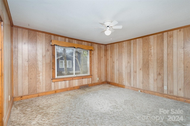 spare room with a textured ceiling, carpet floors, ceiling fan, and wooden walls