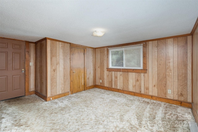 spare room with wooden walls, light carpet, and a textured ceiling