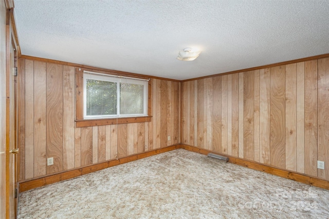 spare room with light carpet, wooden walls, and a textured ceiling