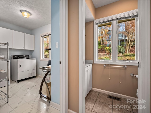 washroom with cabinets, independent washer and dryer, and a textured ceiling