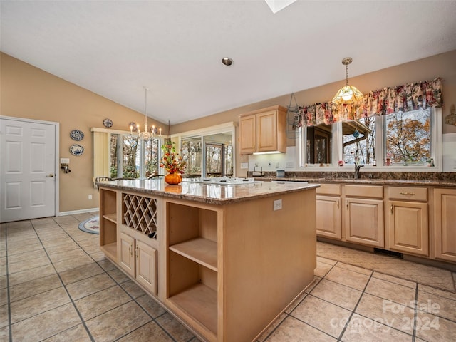 kitchen with light brown cabinets, light stone counters, lofted ceiling, and decorative light fixtures