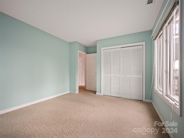 unfurnished bedroom with light colored carpet and a closet