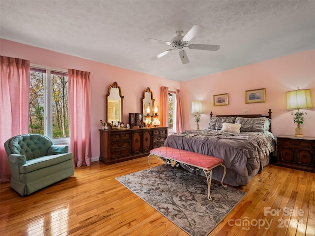 bedroom with a textured ceiling, light hardwood / wood-style floors, and ceiling fan