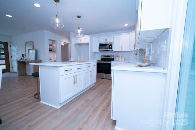 kitchen featuring sink, stainless steel appliances, white cabinets, and hanging light fixtures