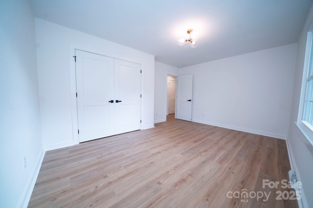 unfurnished bedroom featuring light wood-type flooring and a closet