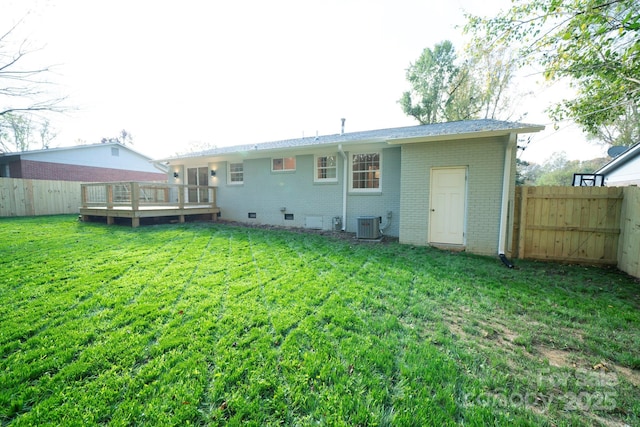 back of property with a yard, a wooden deck, and cooling unit