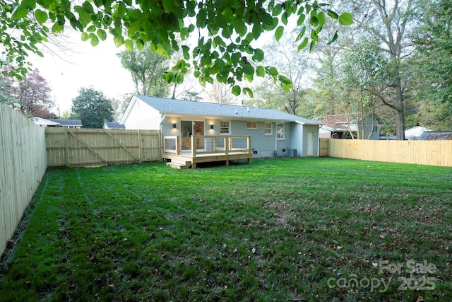 rear view of property with a yard, a wooden deck, and central AC unit