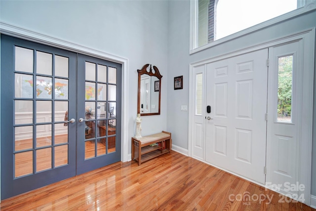 foyer entrance featuring hardwood / wood-style floors, a towering ceiling, and french doors