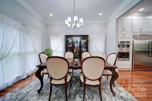 dining space with crown molding, light hardwood / wood-style flooring, and an inviting chandelier