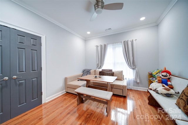 living area featuring ceiling fan, light wood-type flooring, and ornamental molding