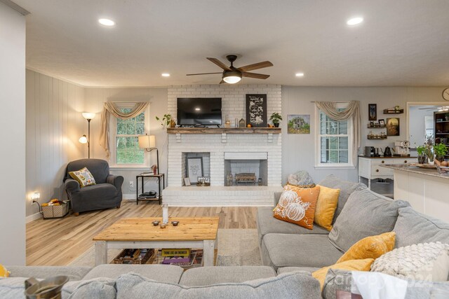 living room featuring hardwood / wood-style floors, ceiling fan, and a brick fireplace