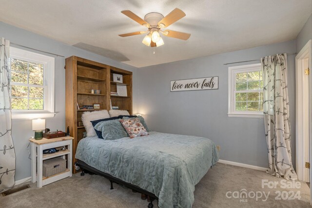 carpeted bedroom featuring multiple windows and ceiling fan