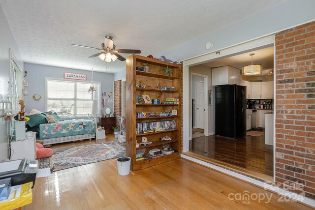 living room with hardwood / wood-style floors, ceiling fan, and a textured ceiling