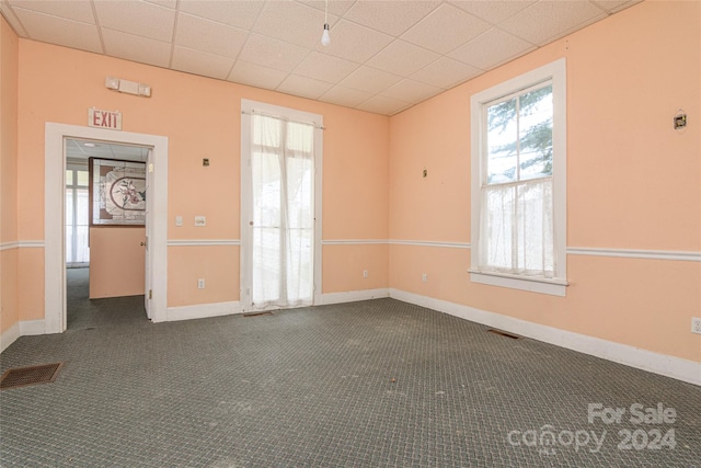 spare room featuring a paneled ceiling and dark carpet