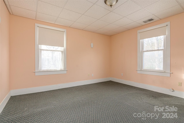 unfurnished room featuring carpet flooring and a drop ceiling