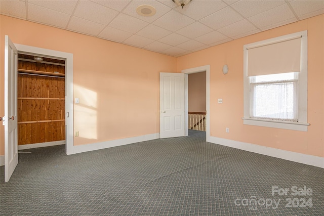 carpeted empty room featuring a drop ceiling