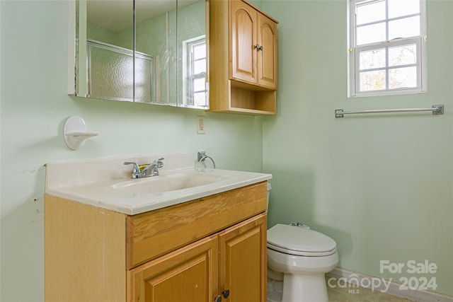 bathroom featuring tile patterned flooring, vanity, an enclosed shower, and toilet