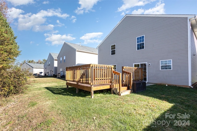 rear view of property featuring a wooden deck and a yard