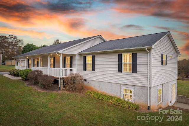 property exterior at dusk featuring a yard and covered porch