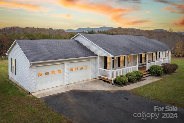 view of front of home with a lawn, a garage, a mountain view, and a porch