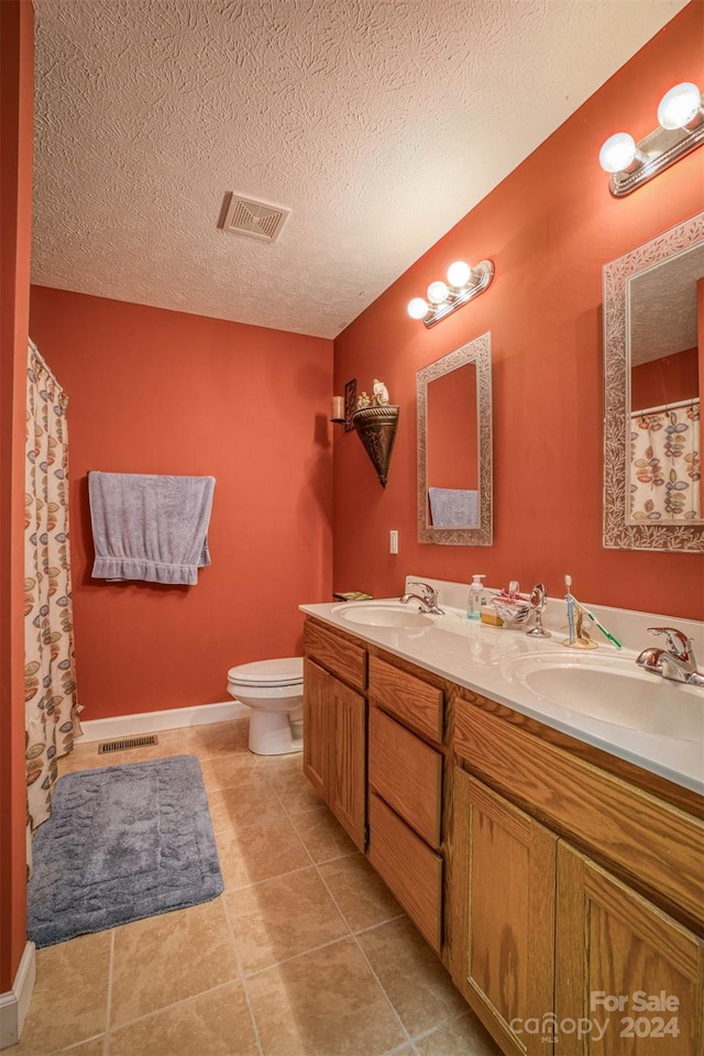 bathroom featuring vanity, tile patterned flooring, a textured ceiling, and toilet