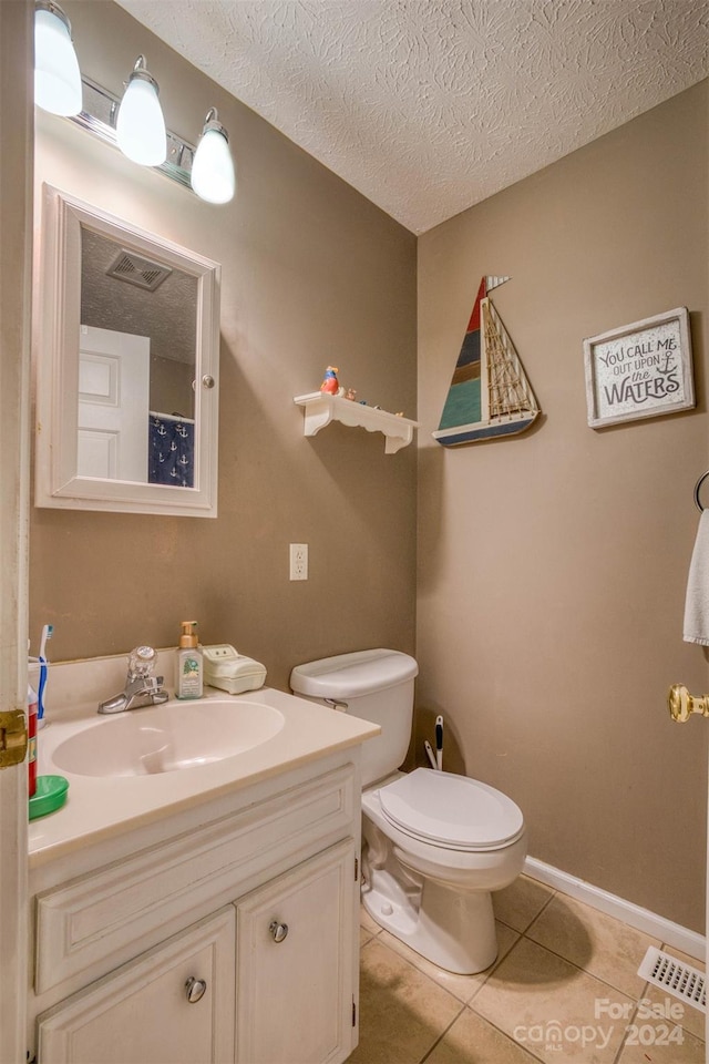 bathroom featuring vanity, a textured ceiling, tile patterned floors, and toilet