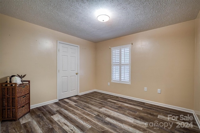 unfurnished room featuring dark wood-type flooring and a textured ceiling