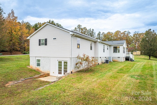 back of property featuring central AC and a lawn