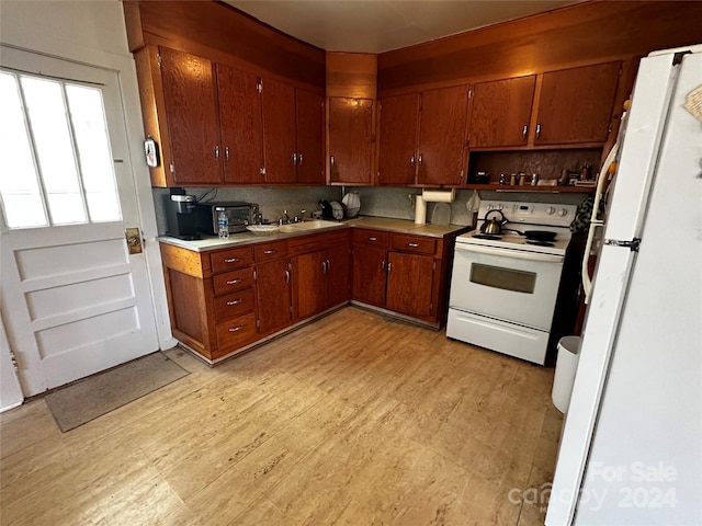 kitchen featuring white appliances, sink, backsplash, and light hardwood / wood-style floors