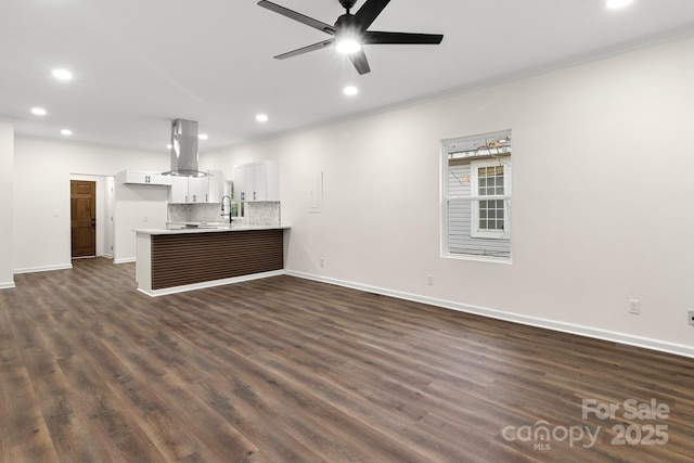 unfurnished living room featuring ceiling fan, sink, dark wood-type flooring, and crown molding