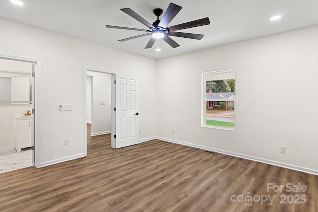 unfurnished bedroom featuring ceiling fan, ensuite bathroom, and dark wood-type flooring