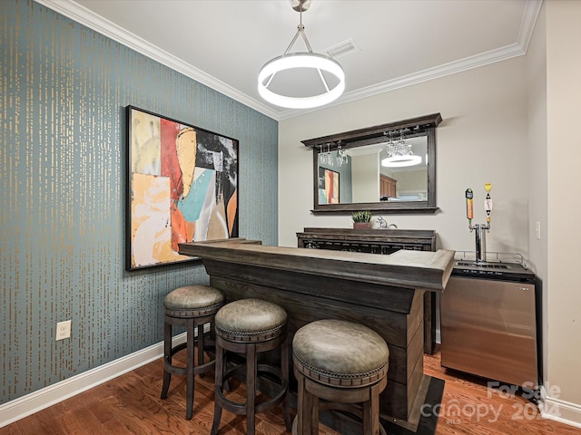 bar featuring hardwood / wood-style flooring, decorative light fixtures, and ornamental molding