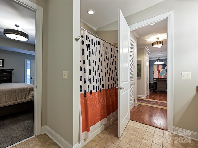 corridor featuring light wood-type flooring and ornamental molding