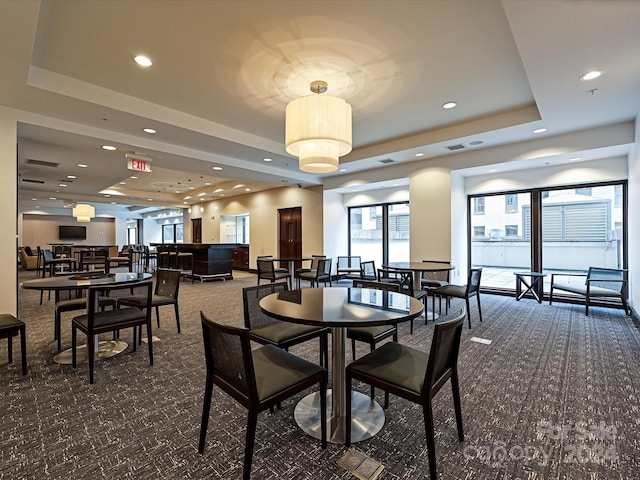 carpeted dining area with a raised ceiling